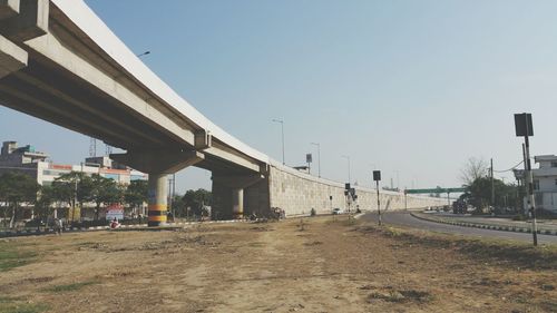 Road by bridge in city against clear sky