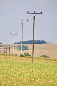 Electricity pylon on field against clear sky