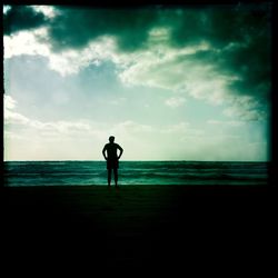 Silhouette man standing on beach against sky