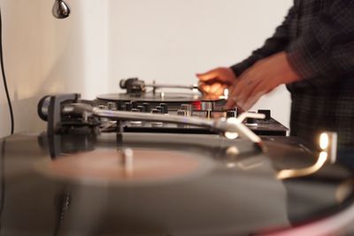 Midsection of man adjusting record on turntable