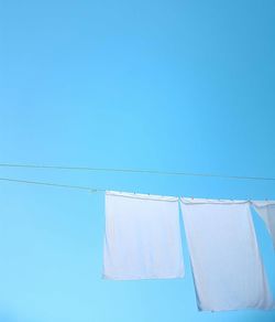 Low angle view of clothes drying against blue sky