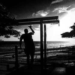 Silhouette of people standing on beach at sunset