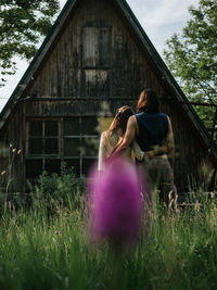 Back view of attractive couple embracing in front of an old wooden house from above