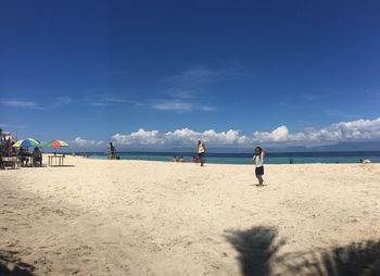 People on beach against blue sky