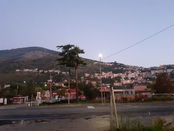 Street by buildings against clear sky