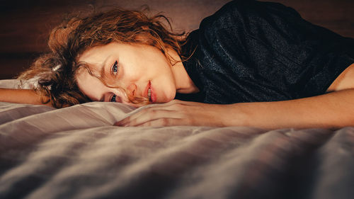 Portrait of young woman lying on bed at home