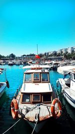 Sailboats moored at harbor against clear blue sky