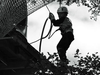 Low angle view of boy playing against sky