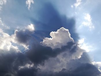 Low angle view of sunlight streaming through clouds