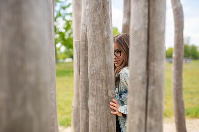 Portrait of woman standing by tree trunk