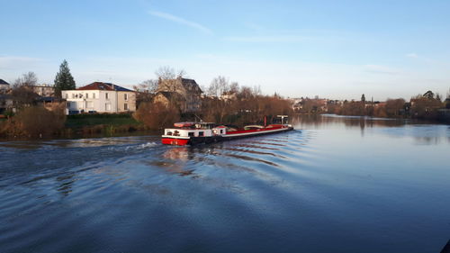 Boat in canal amidst buildings against sky