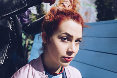 Portrait of redhead woman with friend tying hair