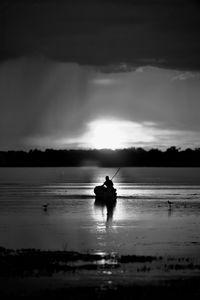 Silhouette person in sea against sky