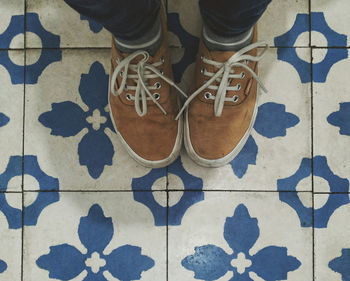 Low section of man standing in front of tiled floor