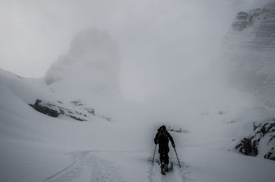 Rear view of man on snow covered mountain during foggy weather