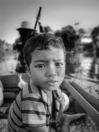 Side view portrait of boy sitting on rowboat in river