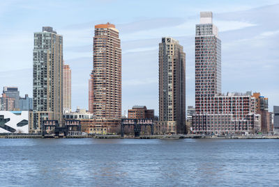 Sea by buildings against sky in city