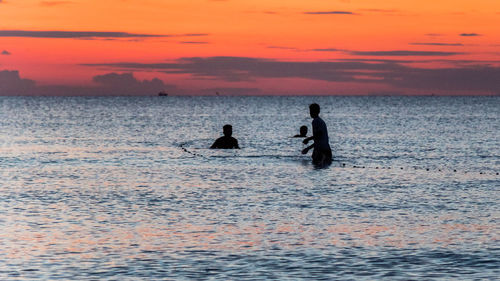 Three fisherman are fishing at sunset on koh rong, cambodia