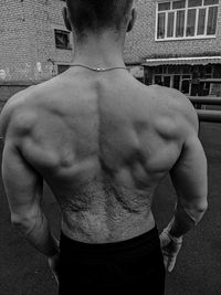 Shirtless man standing against wall