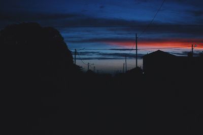 Silhouette electricity pylon against sky at dusk