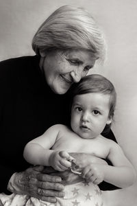 Old gray-haired grandmother sits with a small grandson in the studio