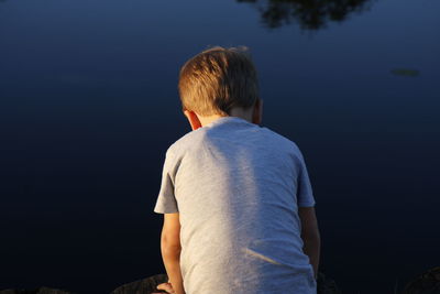 Rear view of boy against lake
