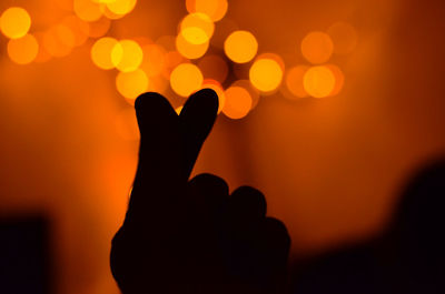 Silhouette hand holding heart shape against sky during sunset