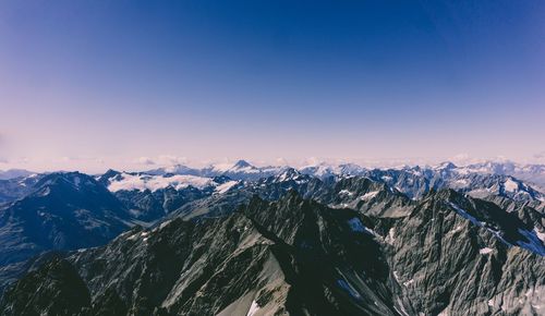 Scenic view of snow covered mountains against blue sky