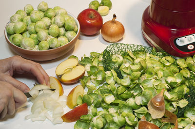 Cropped hand of person cutting onions on table