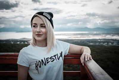 Portrait of smiling young woman standing against sea