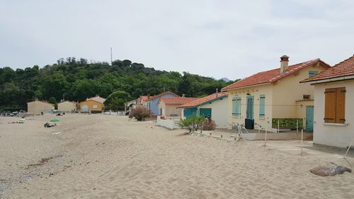 Houses on beach by buildings against sky