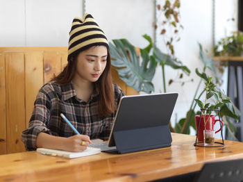 Young woman using phone while sitting on table