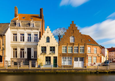 Buildings by river against sky