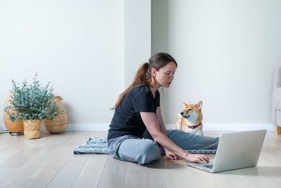 Woman and her dog smiling after  yoga training with online lesson. healthy lifestyle