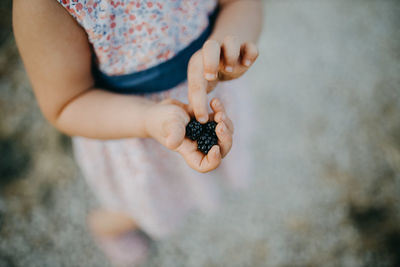 Close-up of girl hand holding berries outdoors