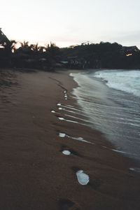 Surface level of beach against sky during sunset