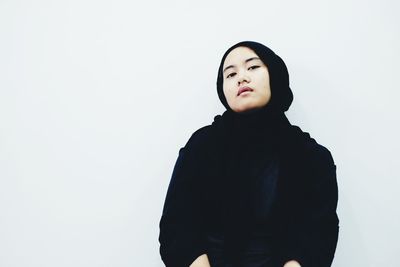 Portrait of young woman wearing hijab against white background