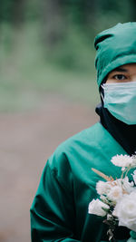 Portrait of woman wearing mask with flowers standing outdoors