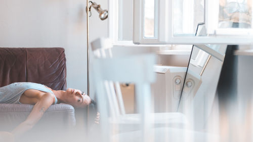 Side view of woman sitting on bed at home