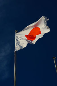 Low angle view of flag against blue sky