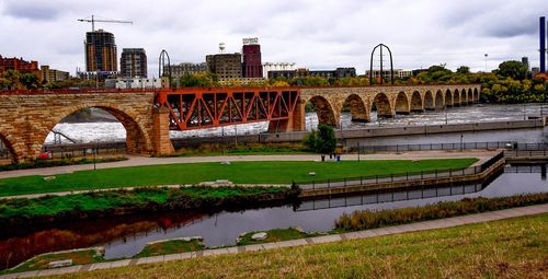 Bridge over river in city against sky