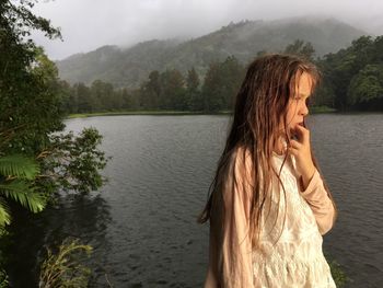 Girl standing by lake against sky