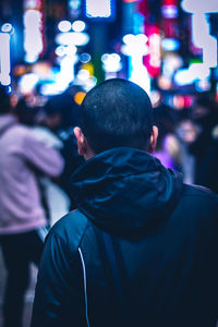 Rear view of man in illuminated city at night