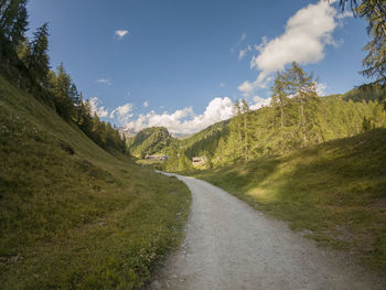 Road amidst green landscape against sky