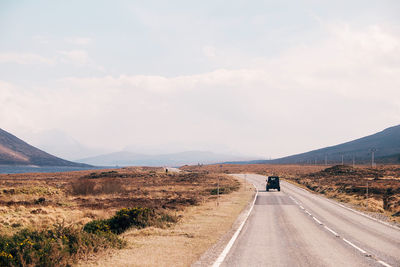 Rear view of man walking on road against sky