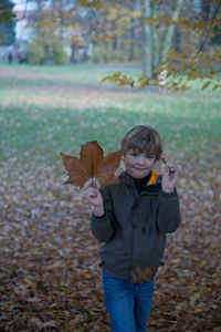 Happy boy standing in park during autumn