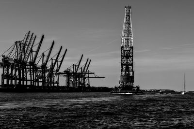 Cranes at commercial dock against sky