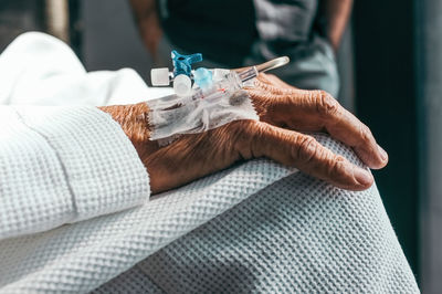 Close-up of medical equipment on wrinkled hand at hospital