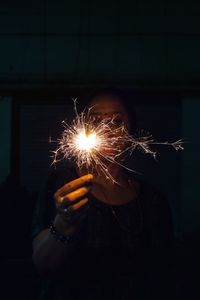 Person holding illuminated sparkler at night on diwali 2020