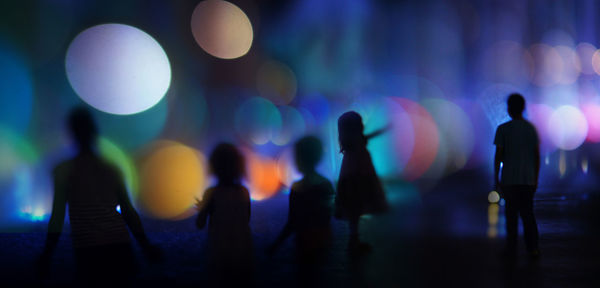 Silhouette people in illuminated city at night